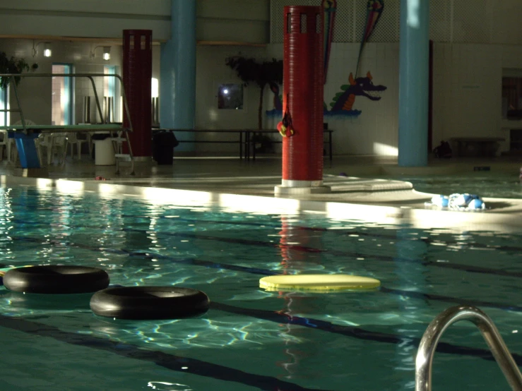 a pool in an empty building with several plastic swimming tires floating around