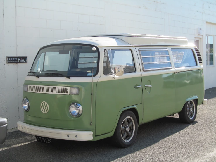 the old volkswagen bus is parked outside on the side of the street