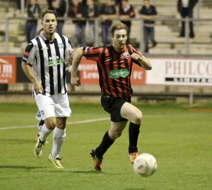 two men are chasing after a soccer ball