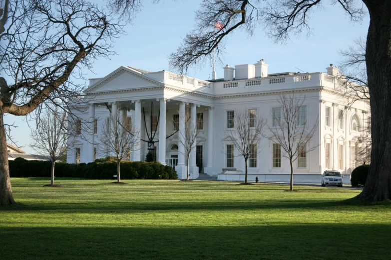 a large white house sitting on top of a lush green field