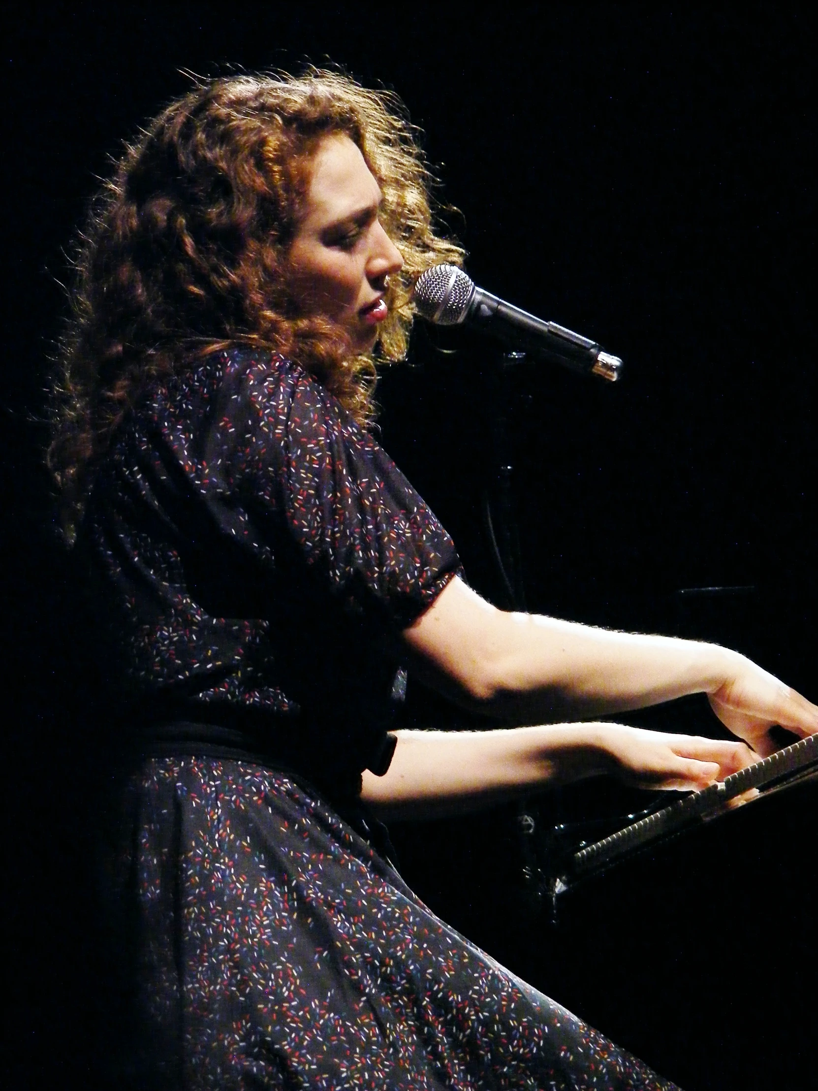 a female performing a song with her keyboard in hand