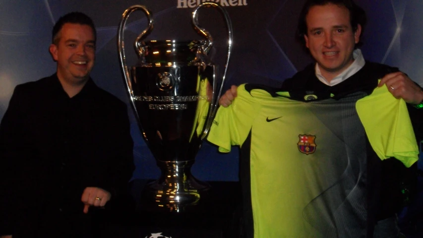 two guys are holding the trophy cup and the shirt