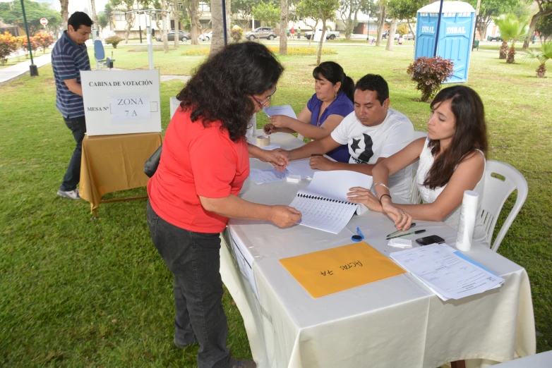 a woman holding a pen in her hand over papers at a table