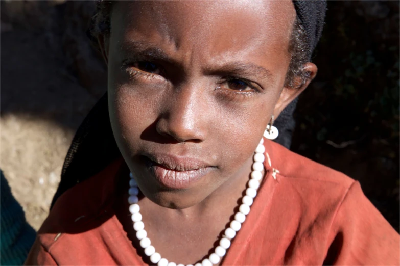 an african woman wearing pearls, earrings and a necklace
