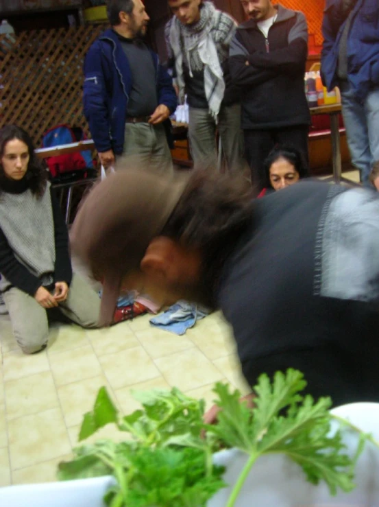 blurry image of a man reaching over the bowl of greens