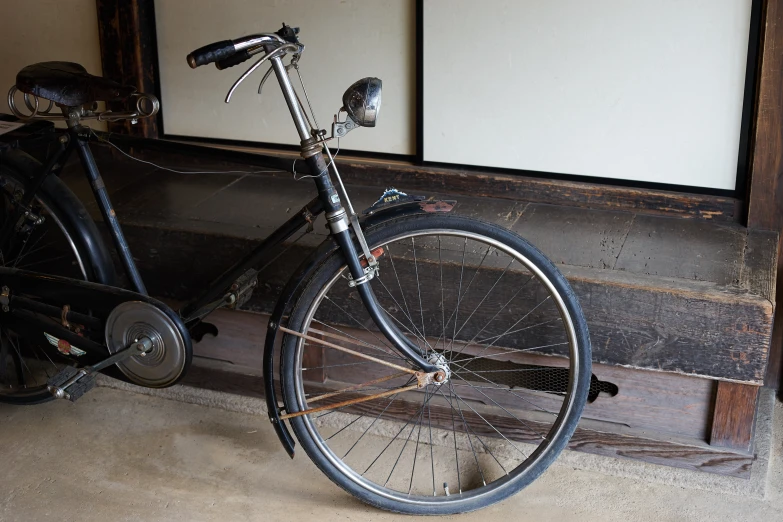 an old bike parked next to a wooden bench