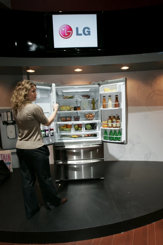 a woman is looking at the refrigerator door open