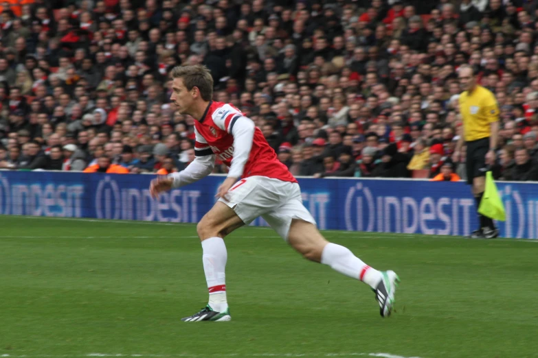 a man playing soccer on the grass in front of a crowd