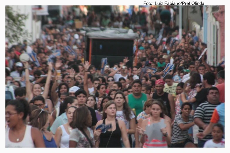 a crowd of people standing in a street next to a stage