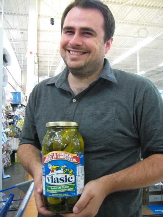 a person that is holding a jar of pickles