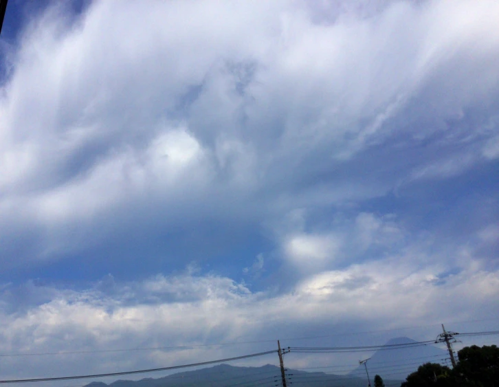 a sky with some clouds and mountains in the distance