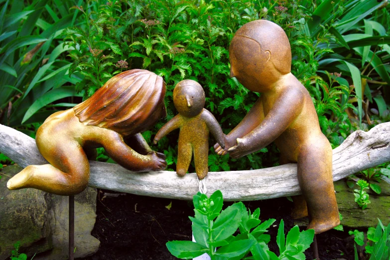 a statue with a young child between two adult sized sitting dolls