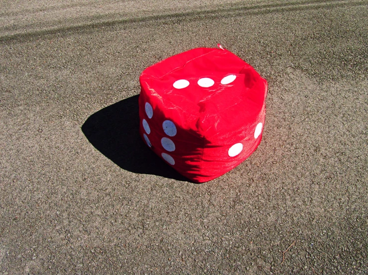 a red dice sitting on the ground with some white spots