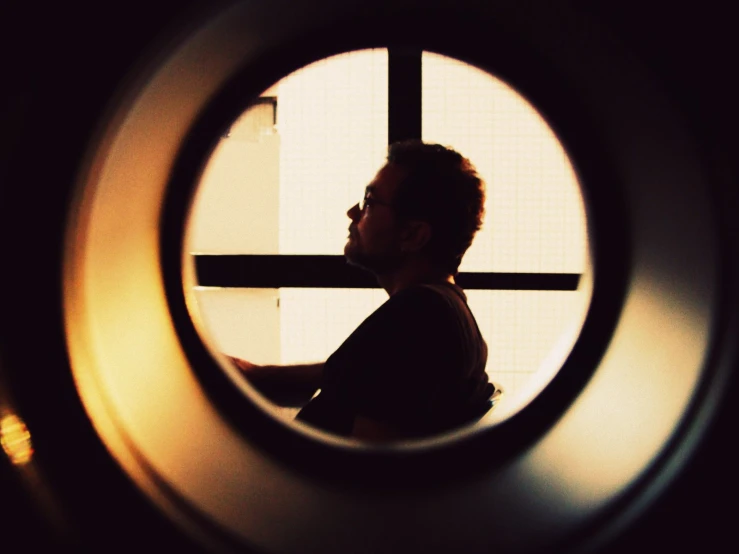 a man sitting in a round window looking out