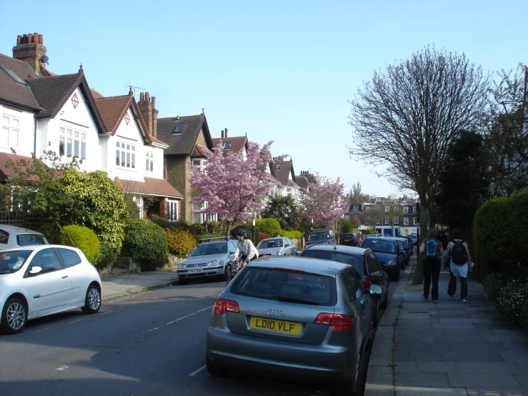 cars parked along a street and people walking down the sidewalk