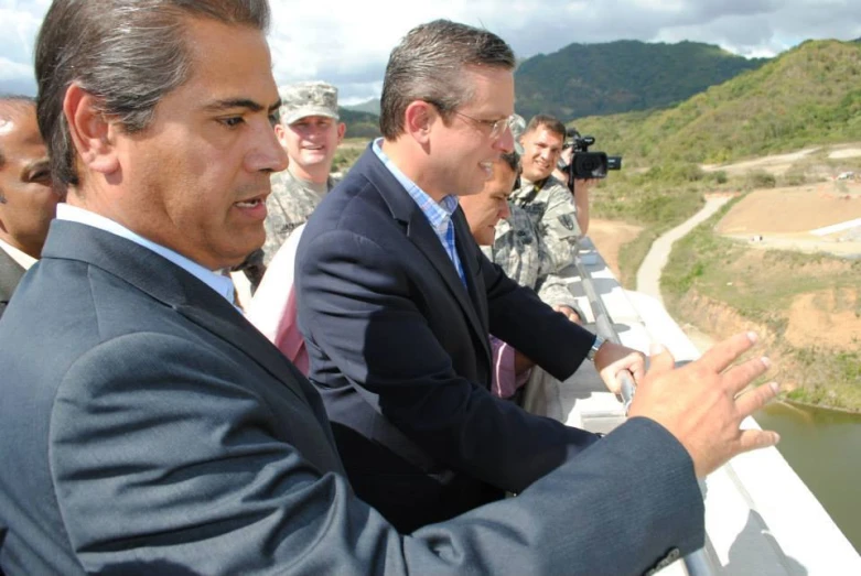 two men in suits shaking hands and several others watching