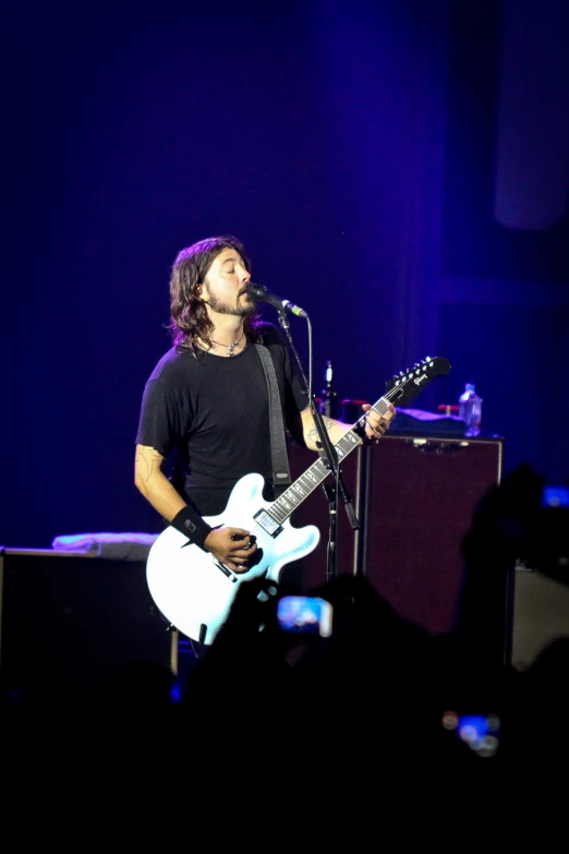 a man on stage holding a white guitar