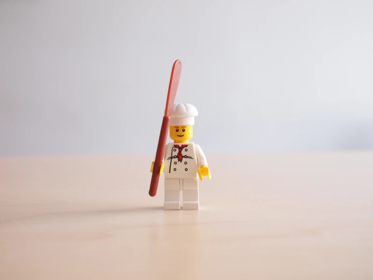 small lego person holding a red and white object