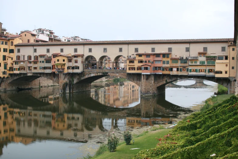 an arched bridge is seen across the river in this city