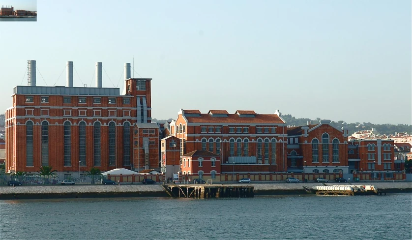 an old brick building with some cranes on top next to the water