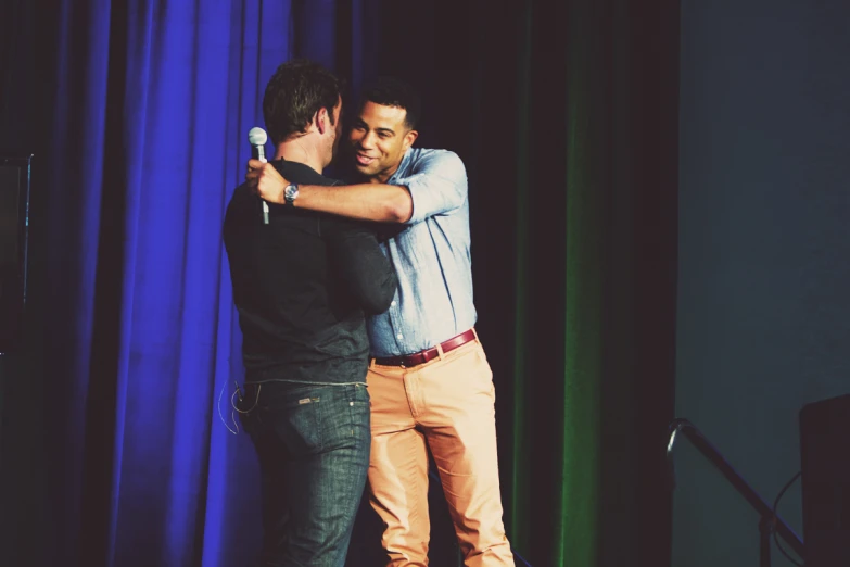 two men hugging on stage in a theatre