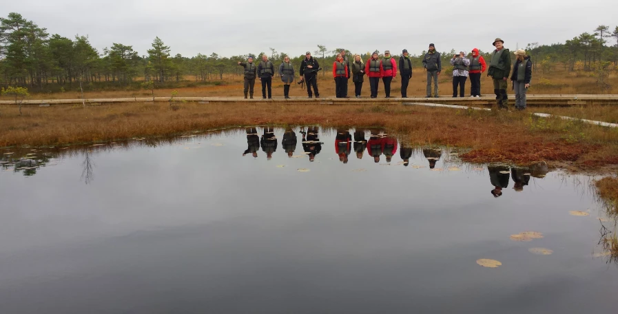 several people standing next to one another and reflecting in the water