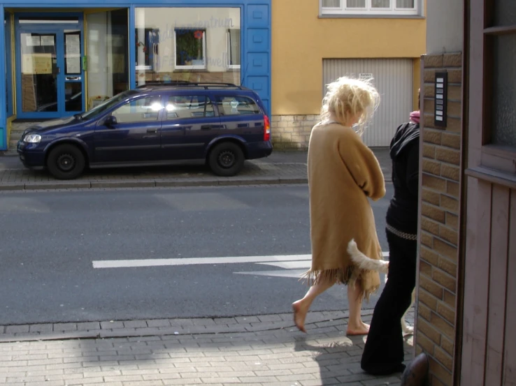 two women walk down a sidewalk between buildings
