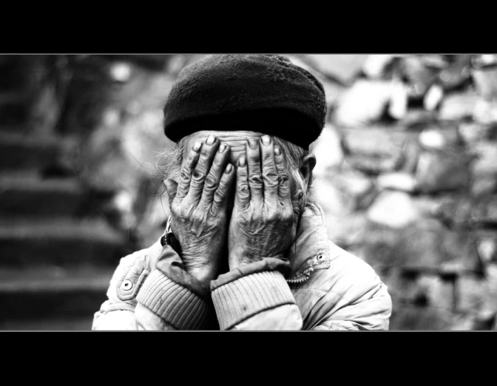 old woman with hands covering her face and eyes