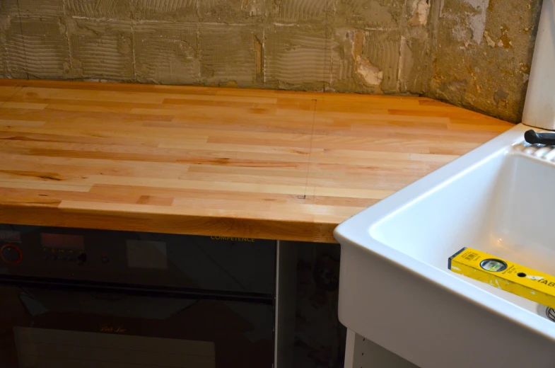 a kitchen counter next to a white sink with a yellow tape