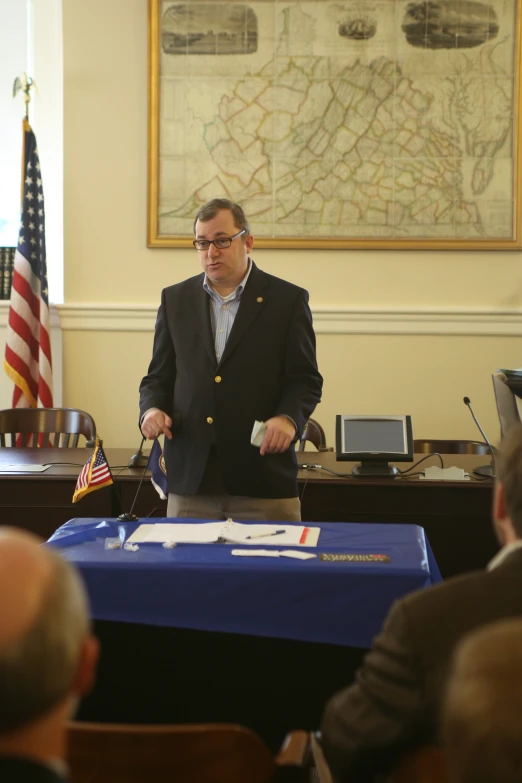 a man in a suit standing at a table in front of a large map