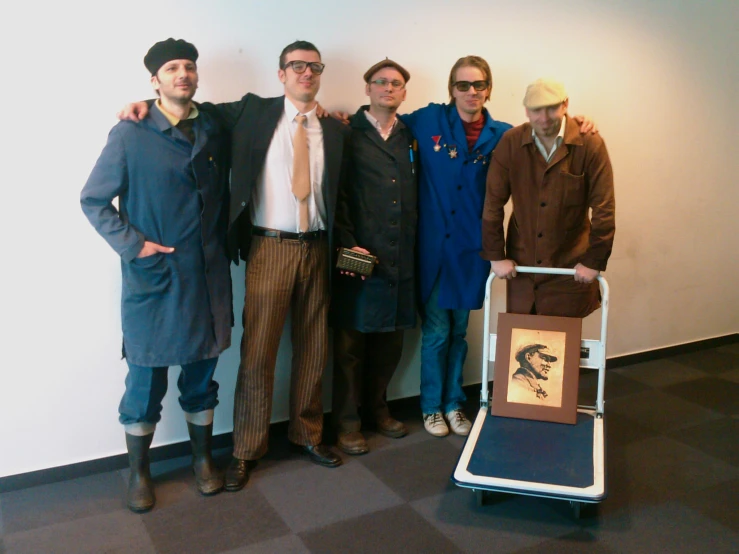 a group of men in coat and ties are posing with a chair