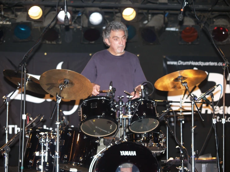 a drummer stands behind his instruments on stage