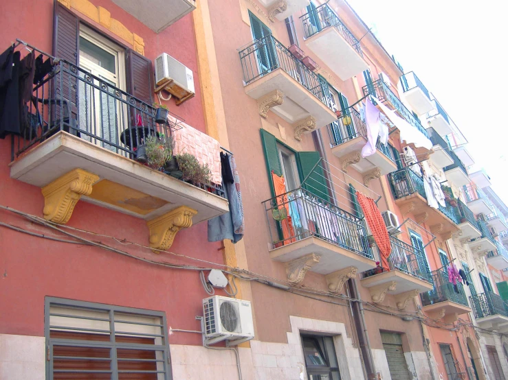 an apartment building that has a balcony and window with colorful curtains