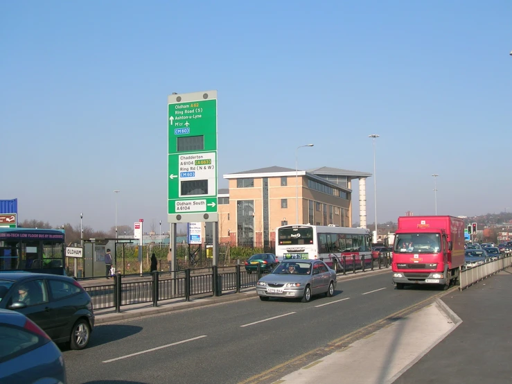 vehicles drive down a street next to a parking lot