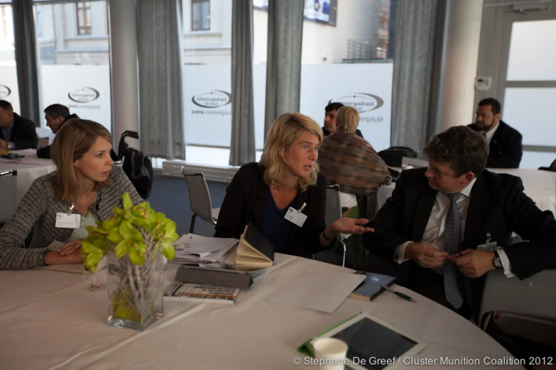 three people sitting at a table listening to soing