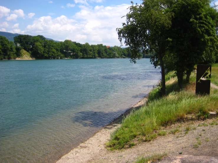 a lake with a bench is surrounded by trees