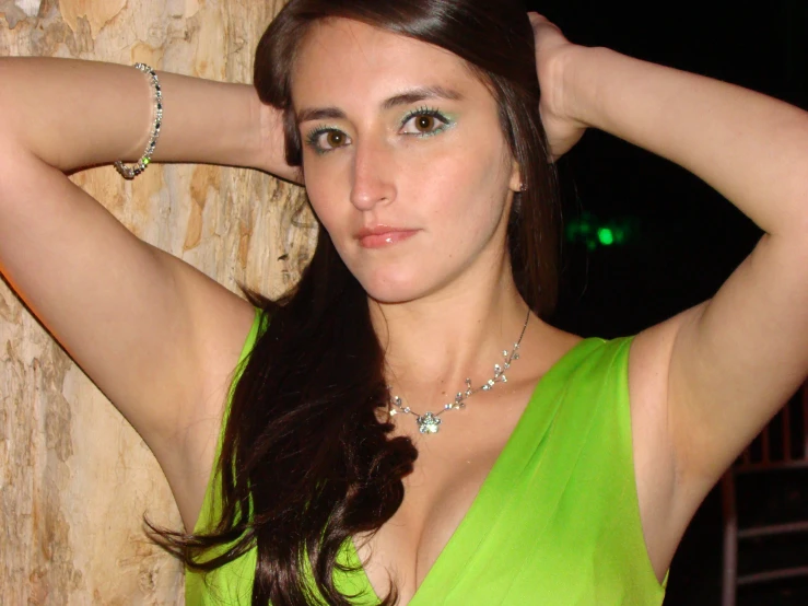 a woman in a neon green dress leaning against a wooden wall