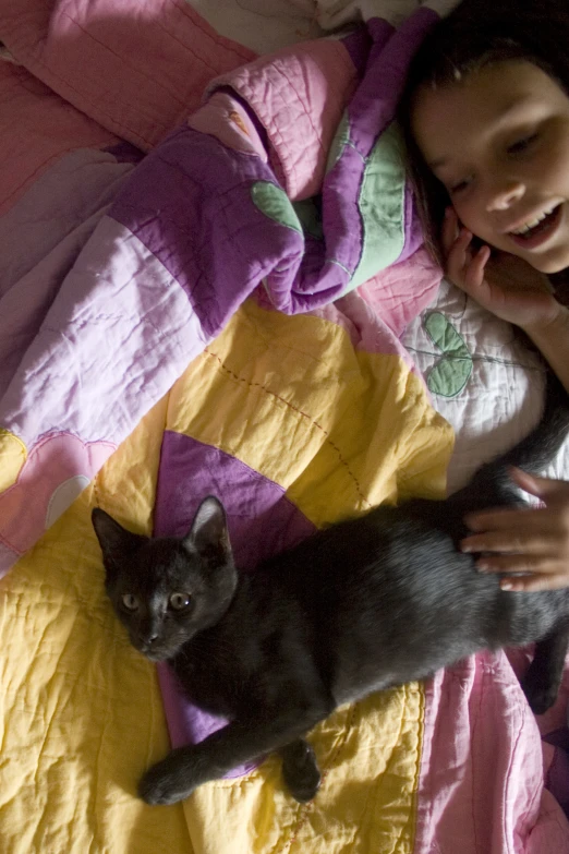 a girl in the bed is laying down next to her cat