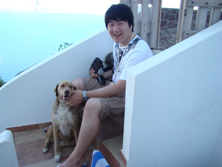 a man sitting on a step with a brown dog