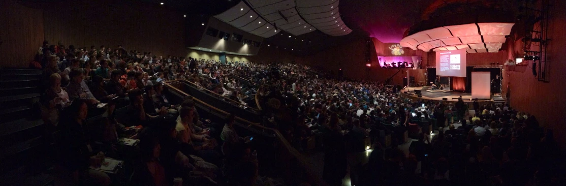 a large room full of people standing around a podium