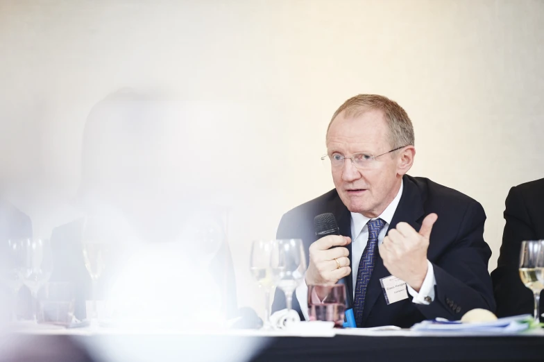 a man sitting at a table talking into a microphone