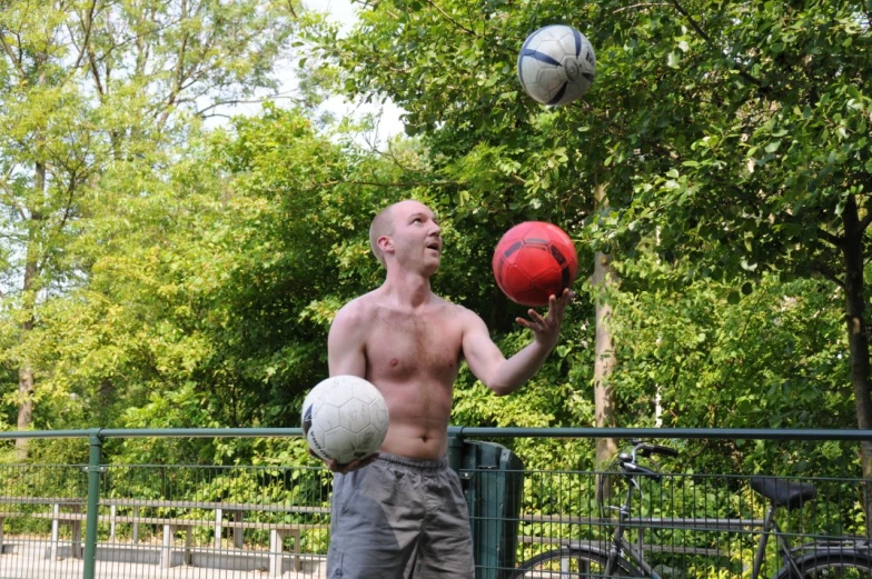 man holding up three balls and balancing them on one