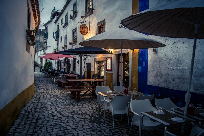 this is a narrow alley in an old town with tables and umbrellas
