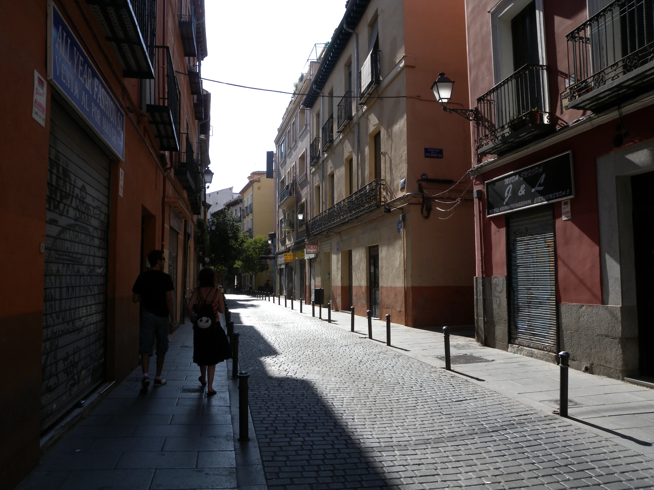 two women walking down a long alley with buildings in the background