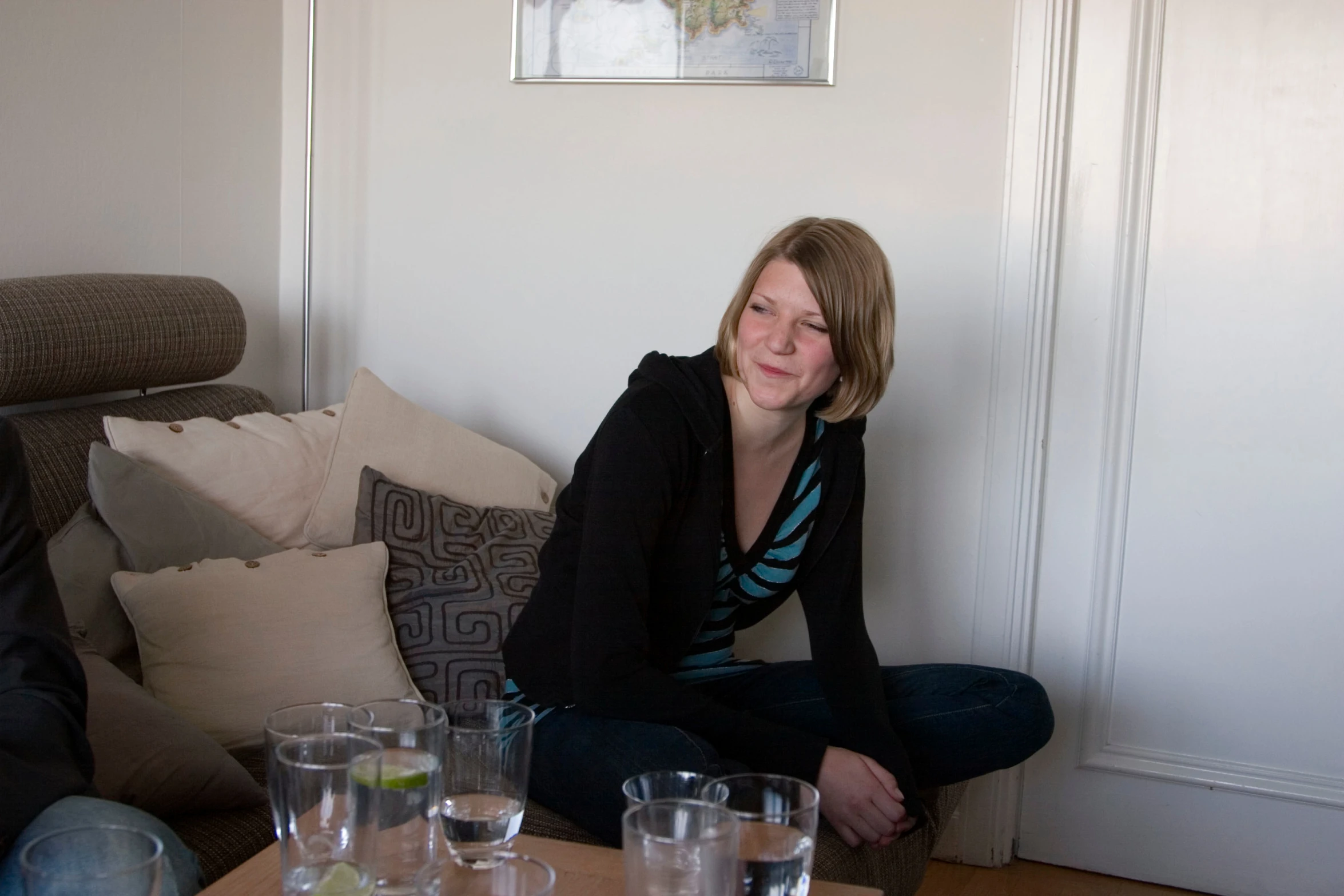 a woman sitting on a couch with a group of empty glasses