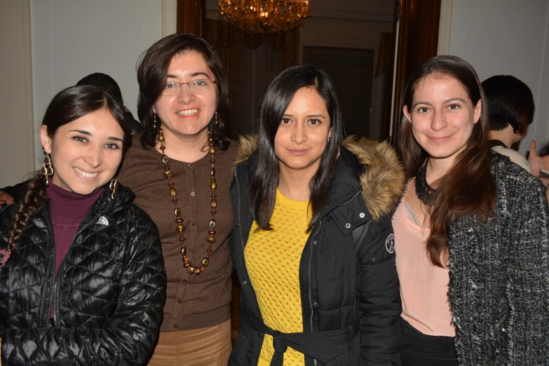 four girls in glasses are standing together at a social event