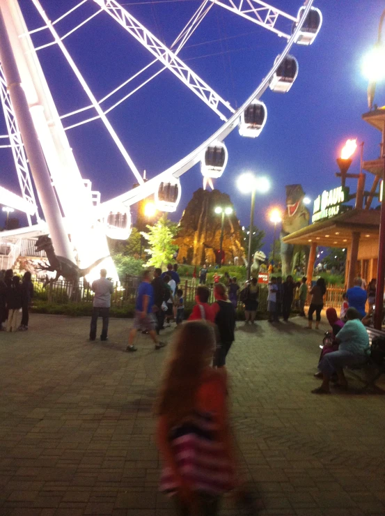 people are sitting on a bench beside a ferris wheel