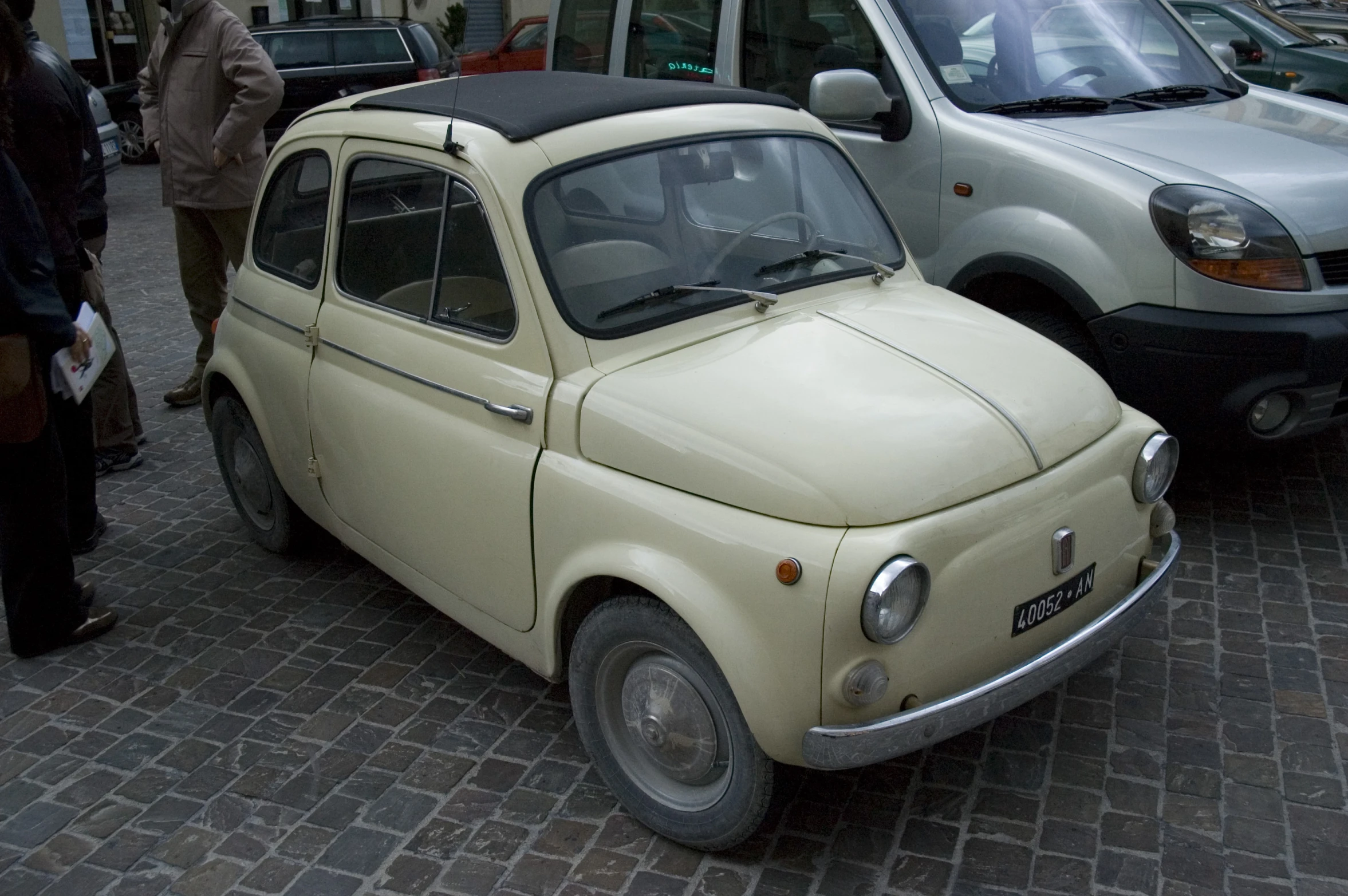 an older version of car parked in front of another small car