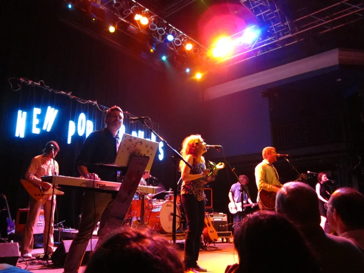 people on stage playing instruments with other musicians in the background