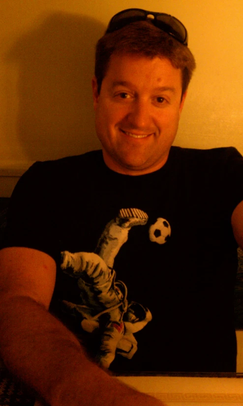 a man smiling wearing a t - shirt and a hat